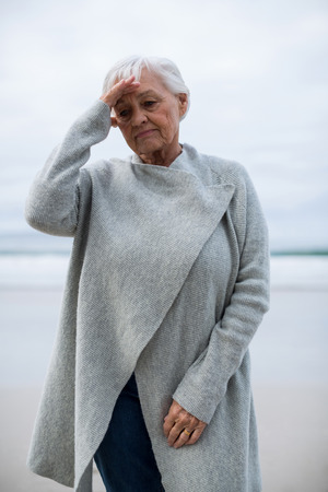 Thoughtful senior woman standing on the beachの写真素材