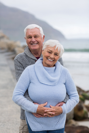 Portrait of senior couple embracing each other on the beachの写真素材