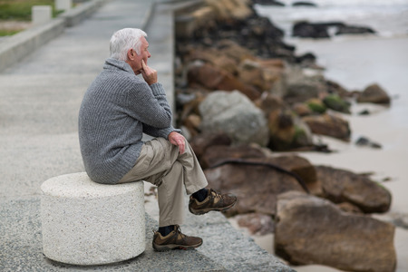 Senior man sitting on the steps near beachの写真素材