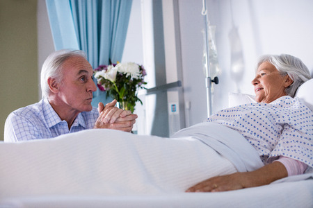 Senior man talking to ill senior patient in hospitalの写真素材
