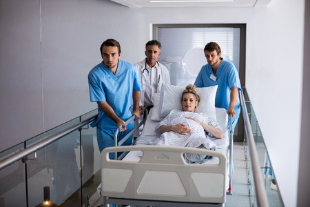 Team of doctors taking a pregnant woman to operation theatre in hospital