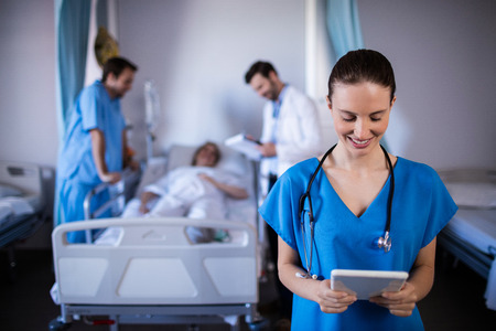 Smiling female doctor using digital tablet in ward at hospitalの写真素材