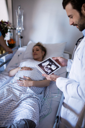 Male doctor looking at sonography report on a digital tablet in the hospitalの写真素材