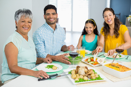 Portrait of happy multi generation family having meal on table at homeの写真素材