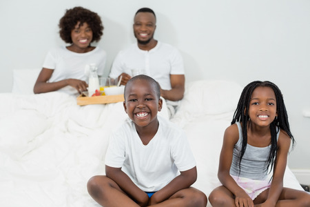 Portrait of kids smiling while parents having breakfast in background at homeの写真素材