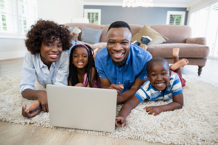 Portrait of happy family using laptop in living room at homeの写真素材