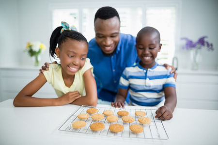 Smiling father and kids looking at cookies on tableの写真素材