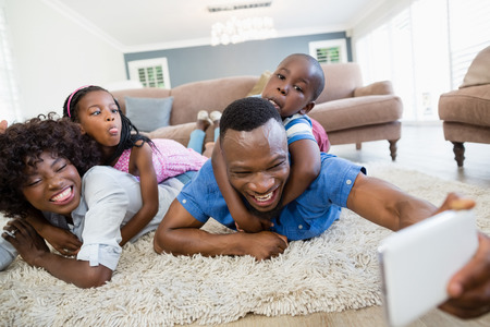 Happy family taking a selfie from mobile phone in living room at homeの写真素材