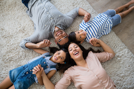 Portrait of happy parents and kids lying on rug at homeの写真素材