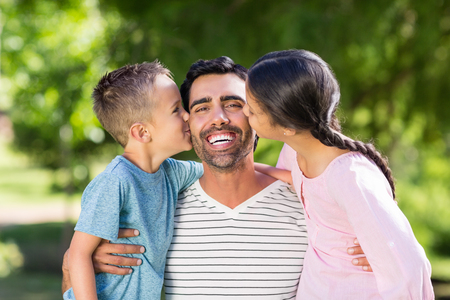 Father having fun with his son and daughter in park on a sunny dayの写真素材