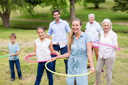 Multi-generation family playing with hula hoop in parkの写真素材