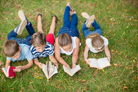 Kids lying on grass and reading books in parkの写真素材