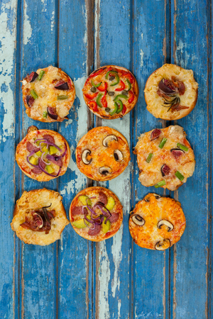 Overhead of various delicious italian pizza served on wooden plankの写真素材