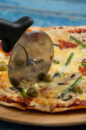 Close-up of delicious pizza served on pizza tray with cutter on pizzaの写真素材