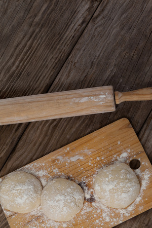Overhead of rolling pin with pizza dough and flour on chopping boardの写真素材
