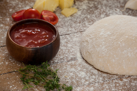 Pizza dough and flour with ingredient on rolling boardの写真素材