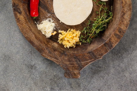 Spices and vegetable with pizza dough in wooden bowlの写真素材