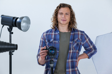 Portrait of photographer holding camera in photo studio