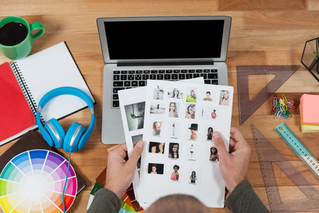 Photographer examining sample photographs at his deskの写真素材