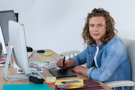 Portrait of photographer working at his desk in officeの写真素材