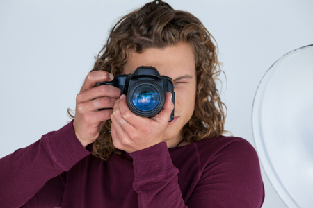 Close-up of photographer clicking a picture using digital camera in the photo studioの写真素材