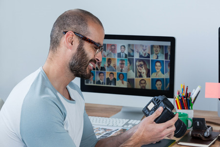 Male photographer reviewing captured photos in his digital camera at studioの写真素材
