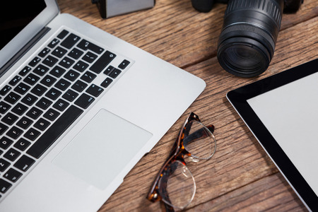 Close-up of digital camera, digital tablet, laptop, spectacle on table in studioの写真素材