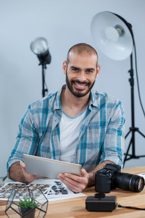Portrait of photographer working over digital tablet at desk in studioの写真素材