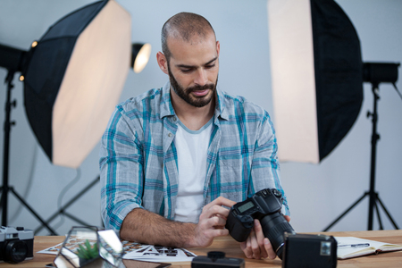 Male photographer reviewing captured photos in his digital camera at studioの写真素材