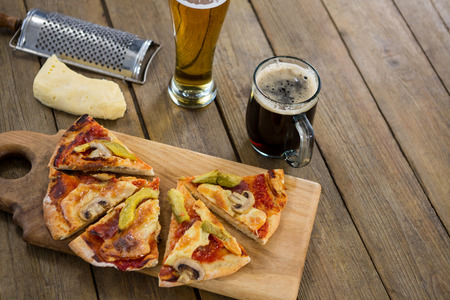 Italian pizza served on chopping board with a mug of beer and glass on a wooden plankの写真素材