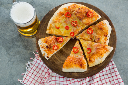 Pieces of italian pizza served with a mug of beer on a pizza trayの写真素材