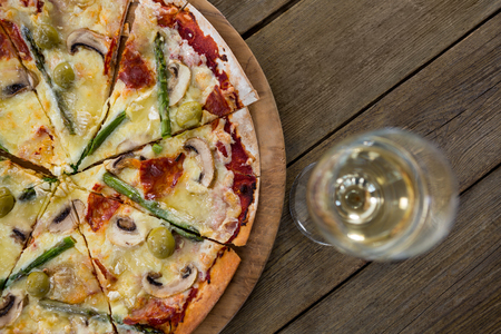Overhead view of italian pizza served on pizza tray with a glass of wineの写真素材