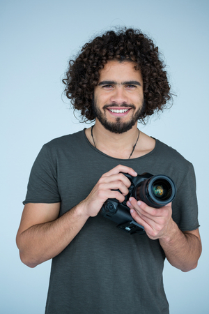 Portrait of happy photographer holding a camera in the studioの写真素材