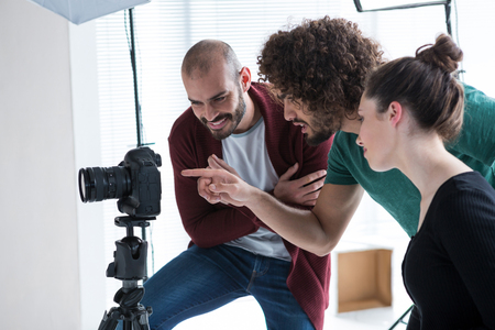 Photographer and his colleagues looking at the photographs in the camera at studioの写真素材