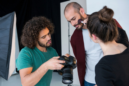 Model looking at photos in the camera while getting ready for a shoot in the studioの写真素材