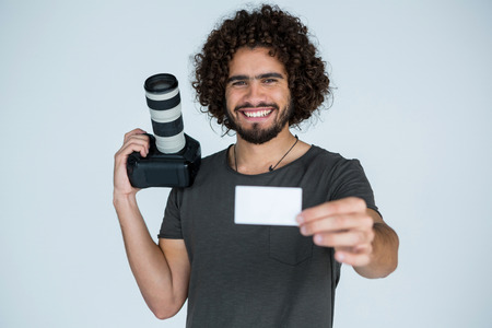 Portrait of male photographer showing visiting card in studio