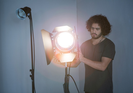 Male photographer adjusting spotlight in studio