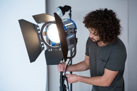 Male photographer adjusting spotlight in studio