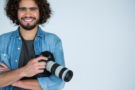 Portrait of happy photographer holding a camera in the studioの写真素材