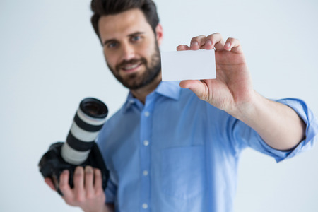 Portrait of male photographer showing visiting card in studio