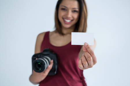 Portrait of female photographer showing visiting card in studio
