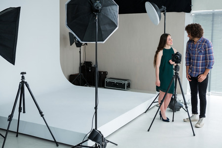 Photographer and female model reviewing captured photos in digital camera at studio
