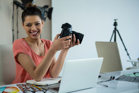 Portrait of female photographer at desk in studio
