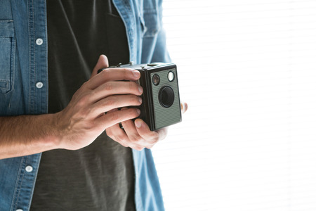 Mid section of male photographer with old fashioned camera against white background