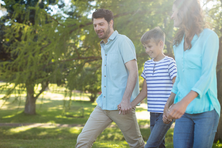 Happy family with hand in hand walking in park on a sunny dayの写真素材