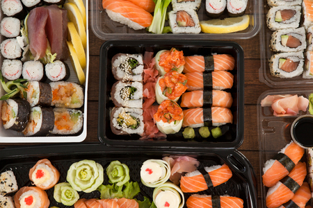 Assorted sushi set served in plastic boxes on wooden tableの写真素材