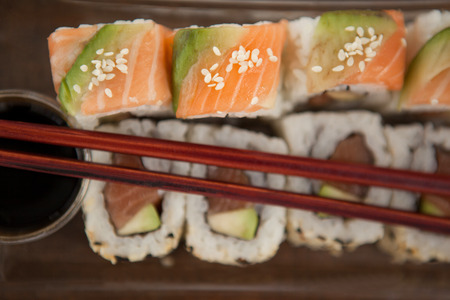 Close-up of uramaki sushi served with chopsticks and soy sauce in plastic plateの写真素材