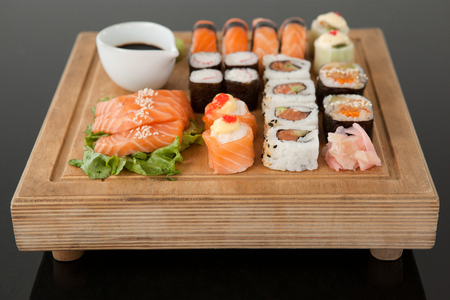 Assorted sushi set served on wooden tray against black backgroundの写真素材