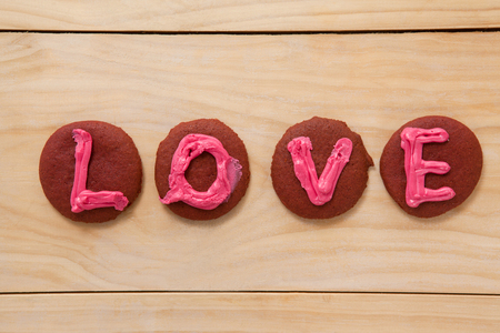 Cookies iced with pink cream displaying love on wooden surfaceの写真素材