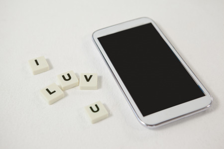 Conceptual image of mobile phone with blocks displaying I love you messageの写真素材